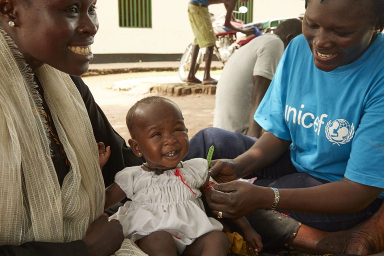 Amira, una bebé de 9 meses, sonrie junto a su mamá y una trabajadora de UNICEF, tras recuperarse de la desnutrición.